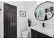 Modern bathroom featuring a black vanity, geometric wall tile, and a round mirror at 5323 Sandy Shell Dr, Apollo Beach, FL 33572