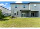 Backyard view of a modern two-story home with a covered patio and well-maintained lawn at 5994 Shiner St, Land O Lakes, FL 34638