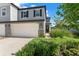 Stylish townhome featuring a two-car garage, stone accents, and lush greenery at 5994 Shiner St, Land O Lakes, FL 34638