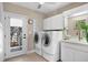 Well-lit laundry room equipped with modern appliances, cabinets, and outdoor access at 611 Brightwaters Ne Blvd, St Petersburg, FL 33704