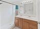 Bright bathroom with a tiled shower and a double sink vanity with wood cabinets and framed mirror at 6512 N 24Th St, Tampa, FL 33610