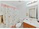 Cozy bathroom features floral shower curtain, white toilet and white vanity with a wood cabinet at 6512 N 24Th St, Tampa, FL 33610