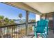 Inviting balcony with blue Adirondack chairs overlooking waterfront and swaying palm trees at 9525 Blind Pass Rd # 301, St Pete Beach, FL 33706