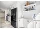 Modern kitchen with stainless steel appliances, white cabinetry, and open shelving for decor at 9525 Blind Pass Rd # 301, St Pete Beach, FL 33706