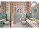 Cozy bathroom with floral wallpaper, blue tiled wainscot, and a framed painting in the center, blending vintage charm and functional design at 1008 Royal Birkdale Dr, Tarpon Springs, FL 34688