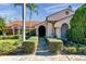 Charming home featuring a meticulously manicured front lawn with manicured bushes leading to a welcoming front entrance at 1008 Royal Birkdale Dr, Tarpon Springs, FL 34688