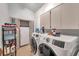 Functional laundry room with modern washer and dryer units, built-in cabinets, and storage shelves at 1008 Royal Birkdale Dr, Tarpon Springs, FL 34688