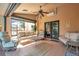 Serene covered patio with comfortable seating, ceiling fan, and a view of the lush backyard and neighborhood at 1008 Royal Birkdale Dr, Tarpon Springs, FL 34688
