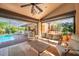 Inviting covered patio with comfortable seating, ceiling fan, and view of the pool and outdoor dining area at 1008 Royal Birkdale Dr, Tarpon Springs, FL 34688