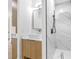 Bright bathroom featuring wood cabinets, a modern vessel sink, and a sleek, glass-enclosed shower with marble-like tiles at 101 W Warren Ave # 1, Tampa, FL 33602