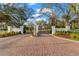 Red brick entryway with white pillars, decorative fence and landscaping enhances the property's curb appeal at 11441 Hammock Oaks Ct, Lithia, FL 33547