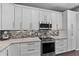 Bright kitchen showcasing stainless steel appliances, granite counters, stylish backsplash, and ample cabinet space at 12956 Royal George Ave, Odessa, FL 33556