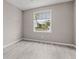 Bedroom with gray walls, wood-look floors, and a window providing natural light and neighborhood views at 17541 Corkwood Bend Trl, Punta Gorda, FL 33982