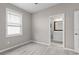 A bedroom with light gray walls, wood-look flooring, and a window with blinds, next to an ensuite bathroom at 17541 Corkwood Bend Trl, Punta Gorda, FL 33982