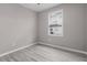 Bedroom featuring gray walls, wood-look floors, and a window with natural light and neighborhood view at 17541 Corkwood Bend Trl, Punta Gorda, FL 33982