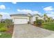 Traditional home with a two-car garage, paver driveway, and manicured lawn and landscaping at 17541 Corkwood Bend Trl, Punta Gorda, FL 33982