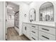 Bathroom with white cabinets, light wood floors, modern fixtures, and elegant mirrors at 2101 Cordova Grn, Seminole, FL 33777