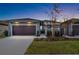Charming home featuring a two-car garage, landscaped yard, and an inviting entryway at dusk at 219 Villa Luna Ln, Lutz, FL 33549