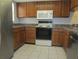 Charming kitchen featuring wood cabinetry, white appliances, and tiled flooring at 233 Woodlake Wynde, Oldsmar, FL 34677