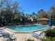 Community pool features lounge chairs, trees, and a nearby building at 233 Woodlake Wynde, Oldsmar, FL 34677