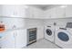 Well-equipped laundry room with white cabinetry, sink, wine cooler, and modern washer/dryer at 301 1St S St # 3103, St Petersburg, FL 33701