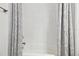 Bright bathroom featuring a white tub with tiled wall and gray patterned shower curtain at 3280 Juniper Springs St, Wesley Chapel, FL 33543