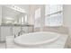 Bright bathroom features soaking tub with marble tile surround and sheer curtains at 3280 Juniper Springs St, Wesley Chapel, FL 33543