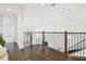 Upstairs hallway featuring hardwood floors, rod iron railing, with staircase and entry to a large bedroom at 3280 Juniper Springs St, Wesley Chapel, FL 33543