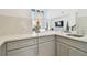 A kitchen featuring neutral countertops, gray cabinets, stainless sink, and open view to the living room at 3280 Juniper Springs St, Wesley Chapel, FL 33543