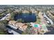 Aerial view of condo community showcasing pond, pool, tennis courts, and mature trees at 3857 Sailmaker Ln, Holiday, FL 34691