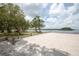 Beautiful beach area with lush trees, picnic tables, and calm blue water at Anclote Gulf Park at 3857 Sailmaker Ln, Holiday, FL 34691