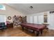 A game room with vaulted ceiling features a pool table with a bookshelf filled with reading materials and comfortable seating at 3857 Sailmaker Ln, Holiday, FL 34691