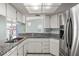 Charming kitchen featuring white cabinets, granite countertops, and stainless steel appliances at 3857 Sailmaker Ln, Holiday, FL 34691