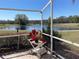 Enjoy serene lake views from this screened patio, framed by lush greenery and a charming decorative cart with red flowers at 4314 Live Oak Blvd, Palm Harbor, FL 34685
