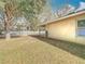 Backyard featuring green grass, trees, and a hose on the side of the house by a white fence at 4441 Fieldview Cir, Wesley Chapel, FL 33545