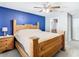 Main bedroom with rustic wooden bed frame, ceiling fan and a blue accent wall at 4441 Fieldview Cir, Wesley Chapel, FL 33545