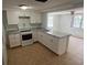 Bright kitchen featuring white cabinetry, granite countertops, and stainless steel appliances, seamlessly flowing into the living area at 5510 Berlin Dr, Port Richey, FL 34668