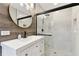 Elegant bathroom showcasing a chic vanity with a round mirror, complemented by a sleek, glass-enclosed shower with a black frame at 7030 19Th N Way, St Petersburg, FL 33702