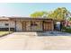 Front exterior with a charming brick facade, covered parking, and a well-maintained front lawn at 7213 Trinity Pl, Tampa, FL 33610