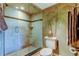 Bathroom with tiled glass shower and toilet near a painted palm tree at 936 Pinellas Bayway S # T-7, Tierra Verde, FL 33715