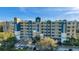 A sunny, multi-story condo building with a tan and blue exterior and multiple balconies overlooks a tree-lined parking area at 960 Starkey Rd # 3406, Largo, FL 33771