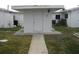 Home exterior featuring white siding, a front door, concrete path, and green yard at 9911 Dahlia N St # 38, Pinellas Park, FL 33782