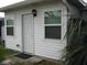 Exterior shot of home with bright white siding, two windows, door and tropical plants nearby at 9911 Dahlia N St # 38, Pinellas Park, FL 33782