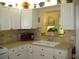 Bright kitchen featuring white cabinets, backsplash, a sink under a window, and modern appliances at 9911 Dahlia N St # 38, Pinellas Park, FL 33782