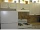 Efficient kitchen design with white cabinets, brick backsplash, and essential appliances at 9911 Dahlia N St # 38, Pinellas Park, FL 33782