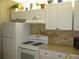 Efficient kitchen featuring white appliances, cabinets, and tile backsplash, with plants above at 9911 Dahlia N St # 38, Pinellas Park, FL 33782