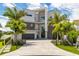 Stunning modern home featuring a beautiful stone and stucco facade with palm trees and a paver driveway at 10100 Tarpon Dr, Treasure Island, FL 33706