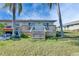 Home's backyard featuring a wood deck, lush green lawn, and vibrant palm trees on a sunny day at 1025 Apollo Beach Blvd # 1, Apollo Beach, FL 33572