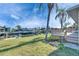 Backyard showcasing waterfront, docks, lush green lawn, and vibrant palm trees on a sunny day at 1025 Apollo Beach Blvd # 1, Apollo Beach, FL 33572