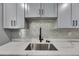 Updated kitchen with stainless sink, tile backsplash, and modern light gray cabinetry at 1025 Apollo Beach Blvd # 1, Apollo Beach, FL 33572